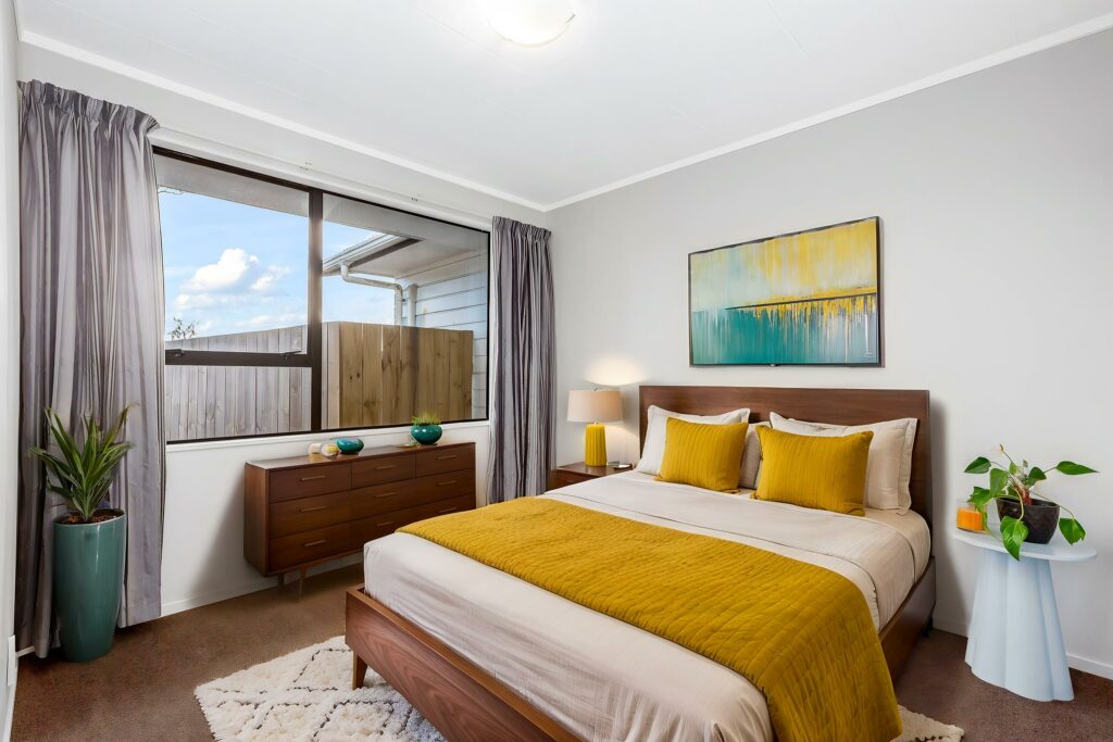 Virtually staged bedroom with warm wood furniture and yellow accents.
