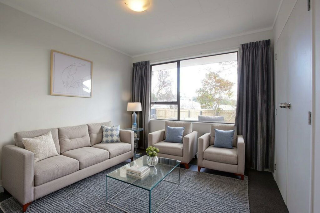 Virtually staged living room with neutral furniture and a glass coffee table.