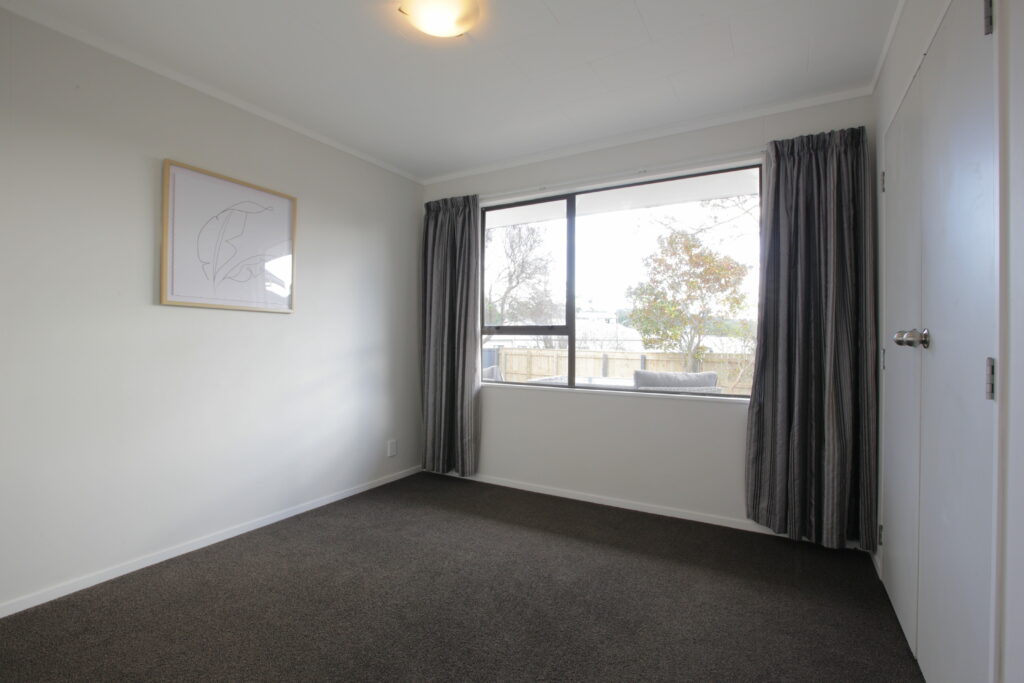 Empty bedroom with dark carpet and gray curtains.