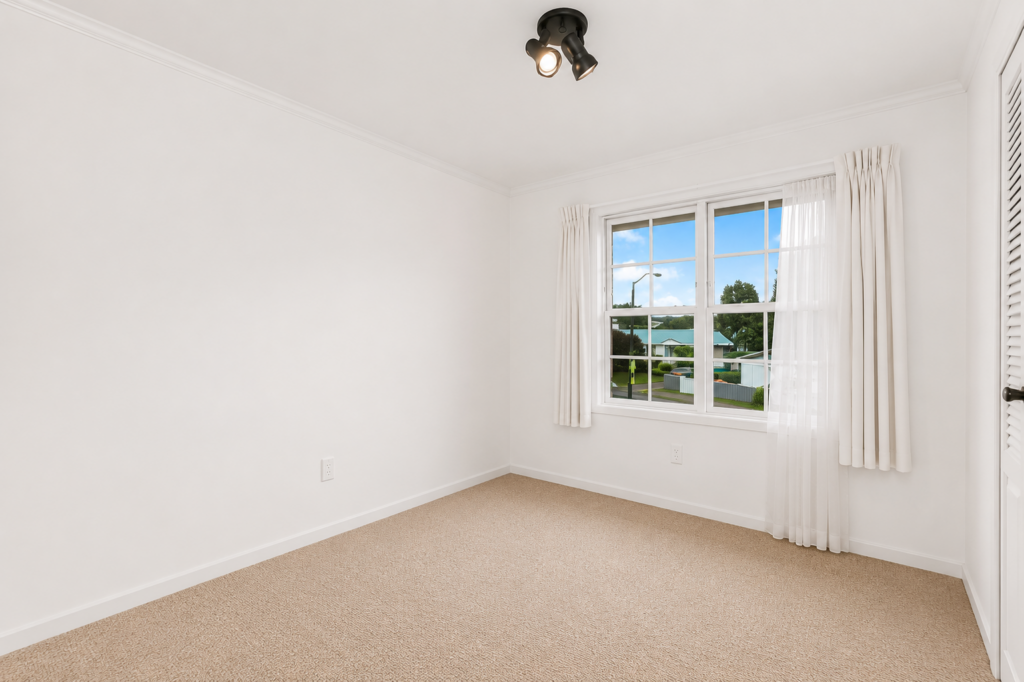 Empty bedroom with neutral carpet and a large window.