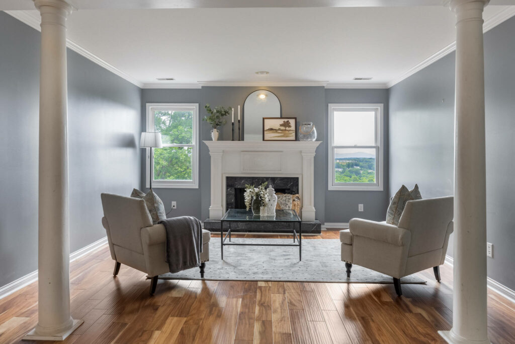 Staged sitting room with fireplace, accent chairs, and hardwood floors.