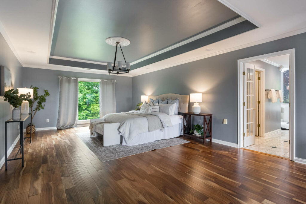Spacious primary bedroom with tray ceiling, hardwood floors, and ensuite bath access.