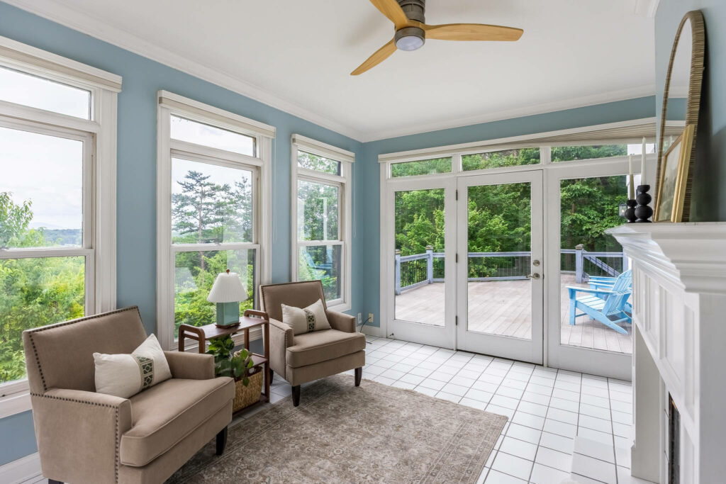 Bright sunroom with accent chairs, large windows, and deck access.