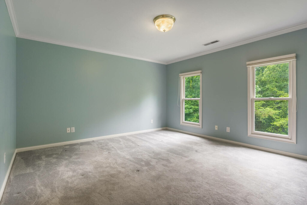 Empty bedroom before virtual home staging with natural light and blue walls.