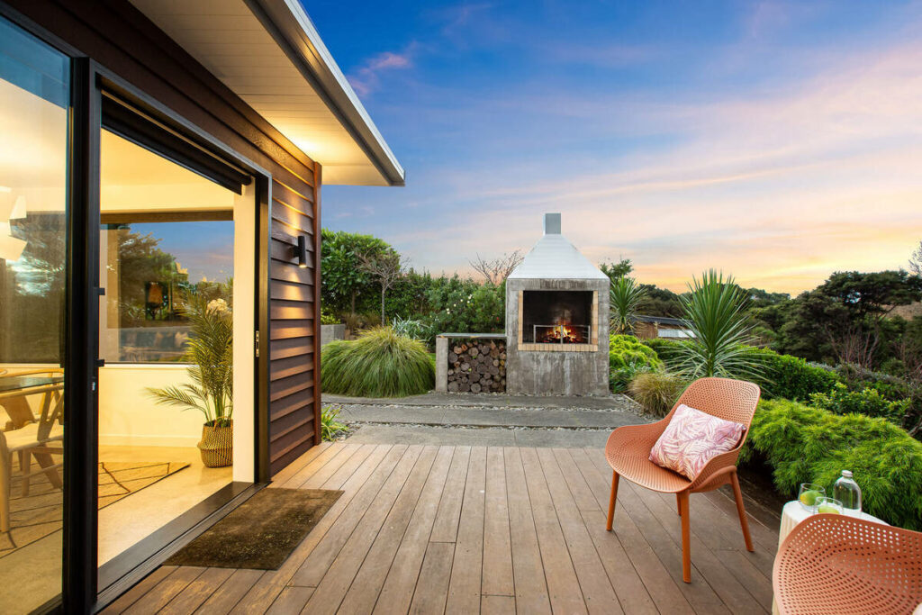 Patio enhanced with twilight sky and glowing outdoor fireplace.