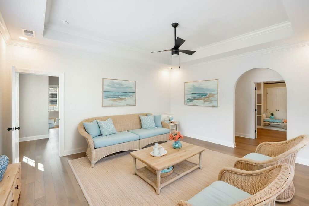 Virtual staged coastal living room with wicker furniture and blue cushions.