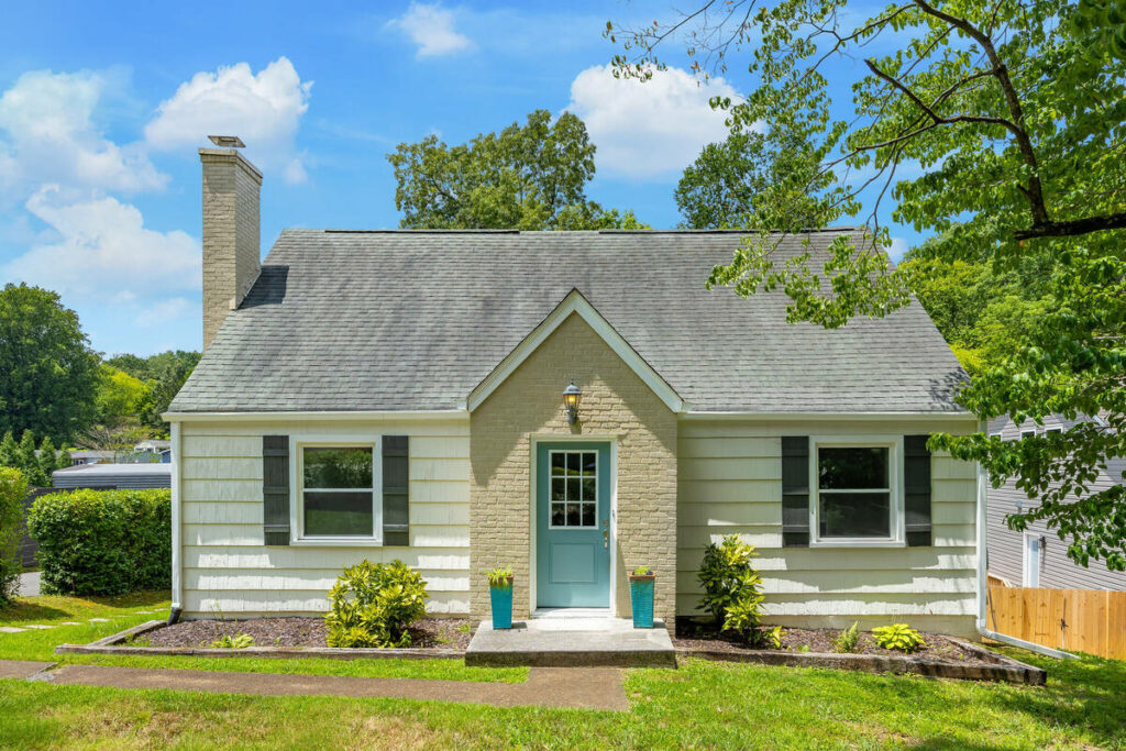 AI real estate photo editing enhancing the curb appeal of a small residential home with a blue front door.