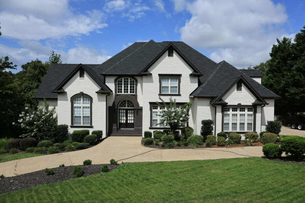 AI real estate photo editing showing a white brick home before color correction and exterior enhancement.
