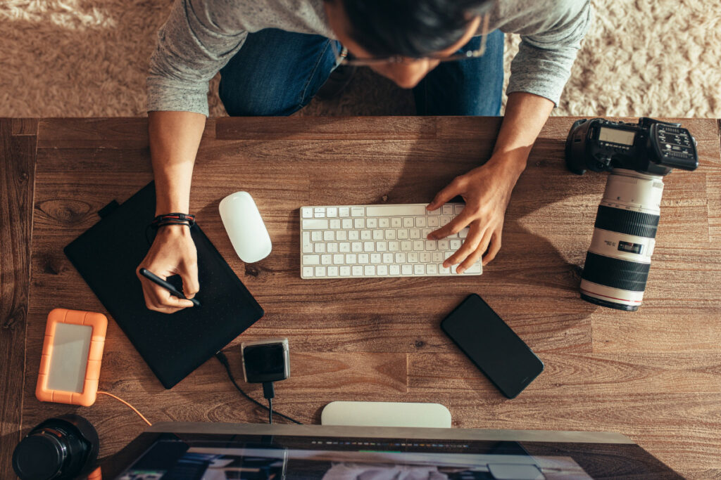 Photographer managing an editing workflow with camera equipment and computer