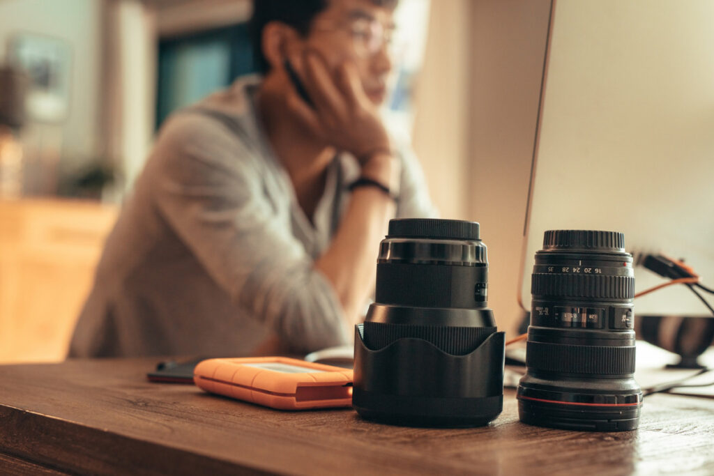 Wedding photo editing workspace with camera lenses and computer