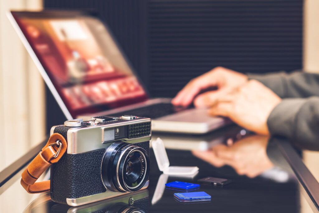 Camera beside a laptop used for AI photo editing