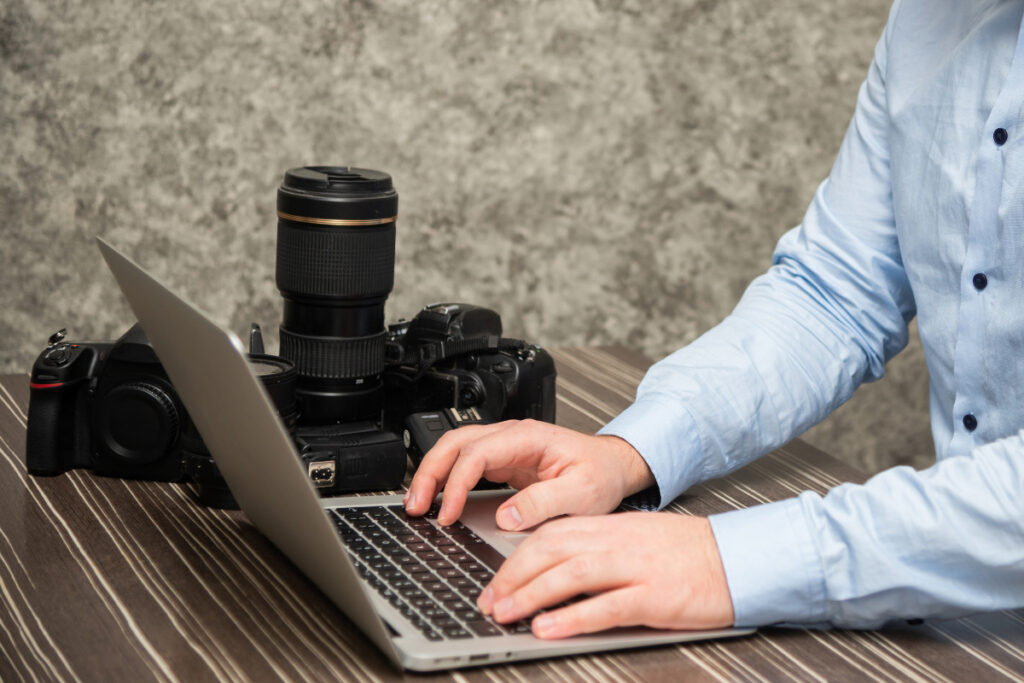 Photographer working on a laptop with AI photo editing tools and camera equipment