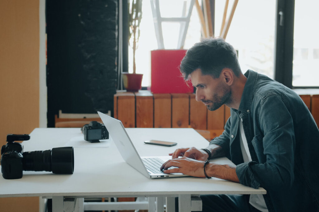 Photographer using an AI real estate photo editing tool on a laptop