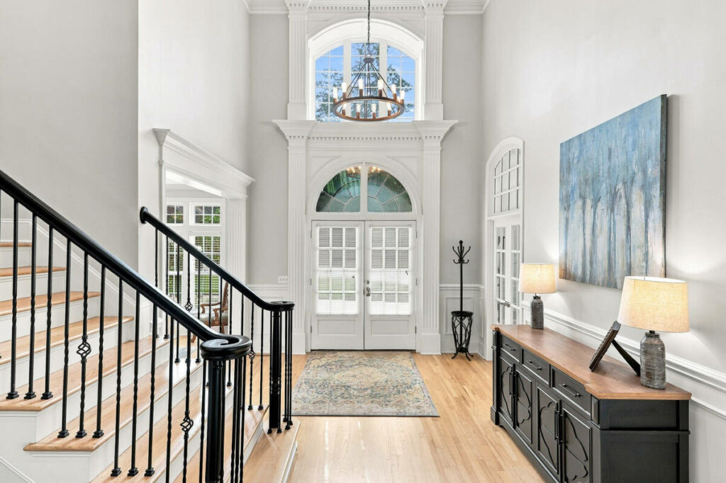 Architecture photography of a luxury entryway with high ceilings, staircase, and arched windows.