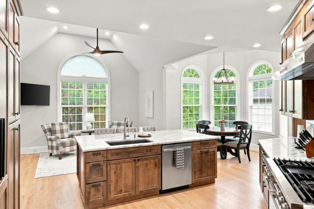 Architecture photography of a luxury kitchen with wood cabinetry, island, and arched windows.
