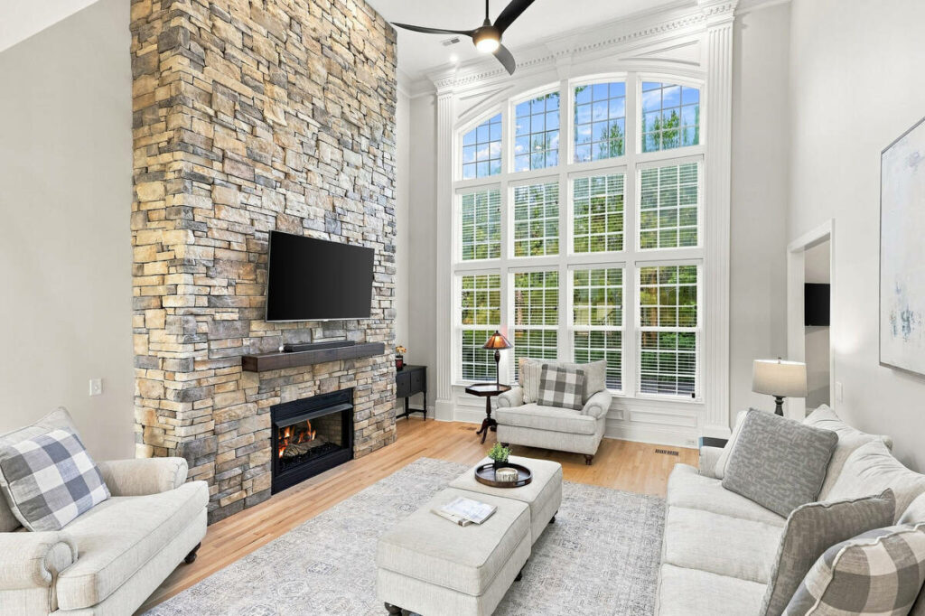 Architecture photography of a living room with a stone fireplace and large arched windows.