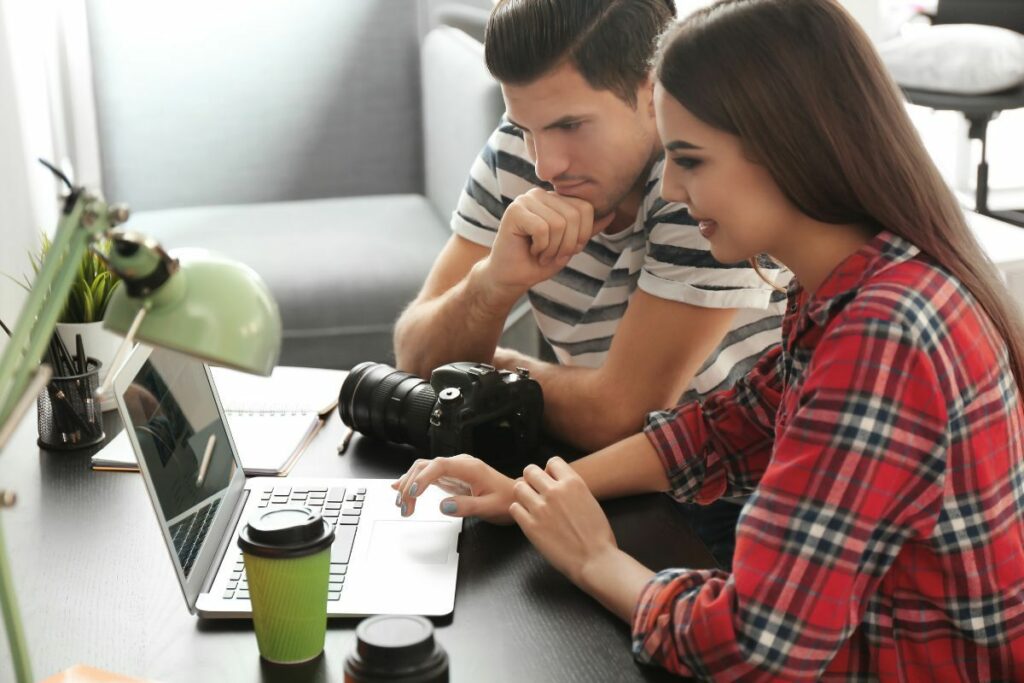 Two photographers working together on AI photo editing with a camera nearby