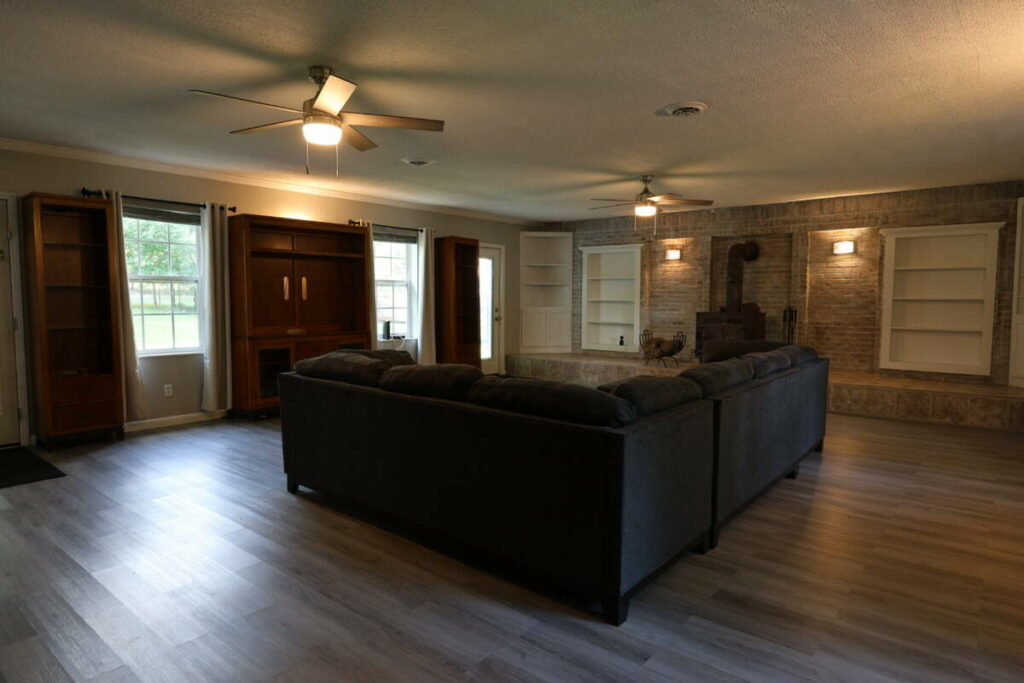 Family room before lens distortion correction showing a dark interior captured with a wide-angle lens.