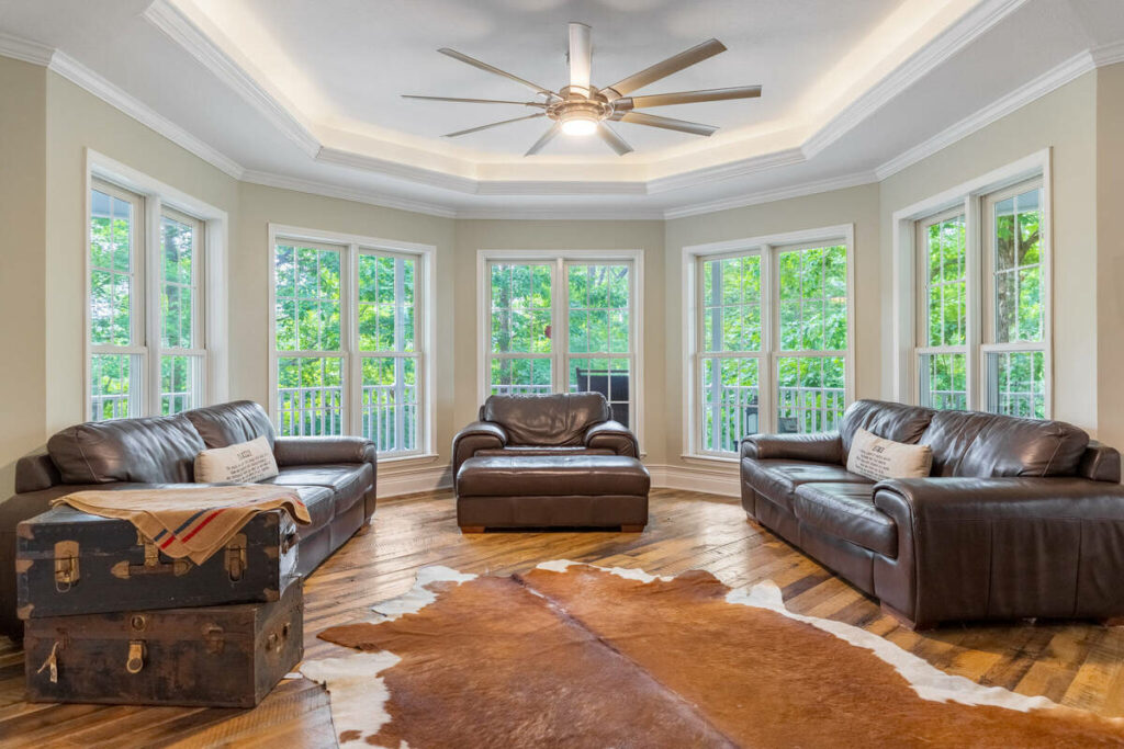 Lens distortion correction on a living room with large windows, leather seating, and straight architectural lines.