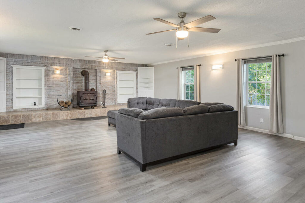 Lens distortion correction applied to a spacious family room with straight walls, windows, and shelving.