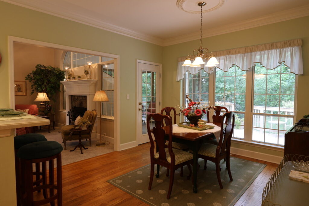 Dining room before lens distortion correction showing warm lighting and wide-angle interior perspective.