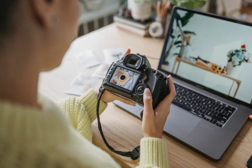 Photographer reviewing images on a camera beside a laptop as part of a photography client workflow