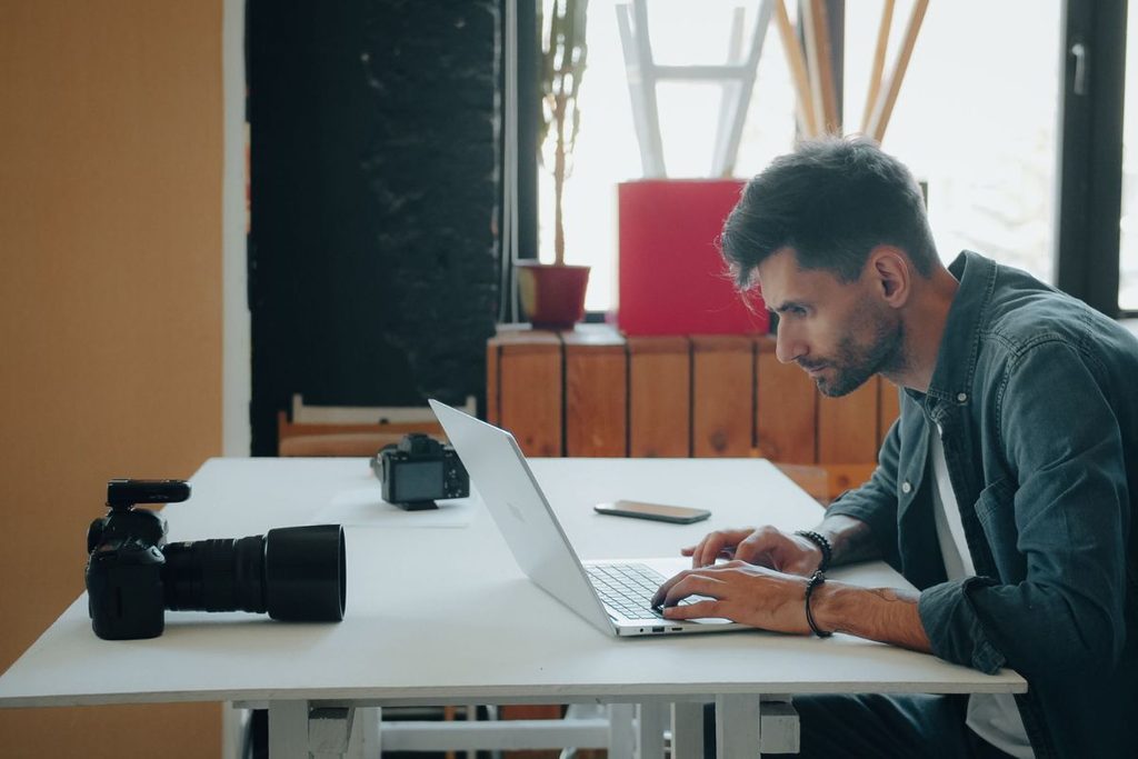 Photography coordinator working on a laptop with camera equipment nearby