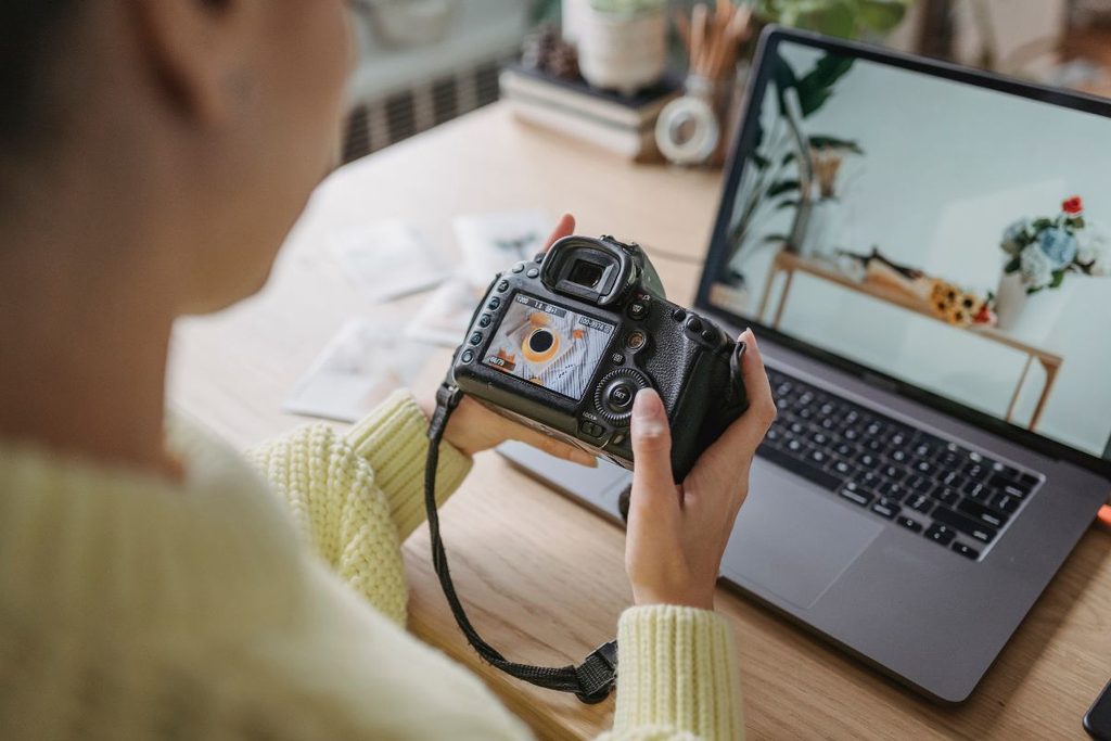 Photography coordinator reviewing images between camera and laptop
