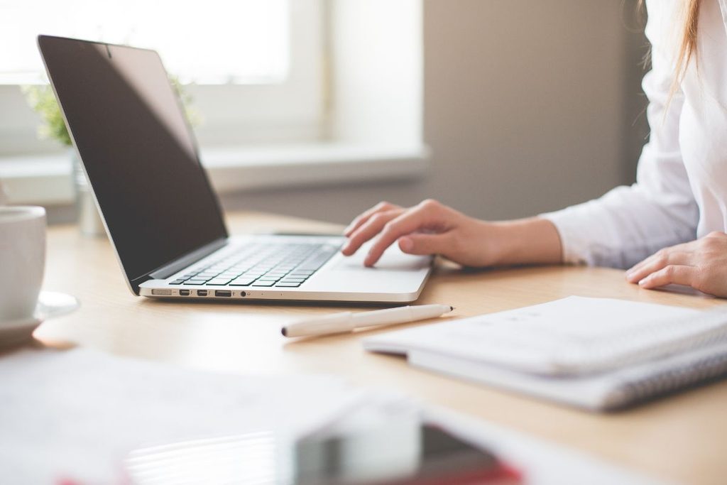 Production coordinator managing photography tasks and workflows on a laptop