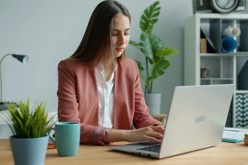 Growth Coordinator working on a laptop in a professional office.